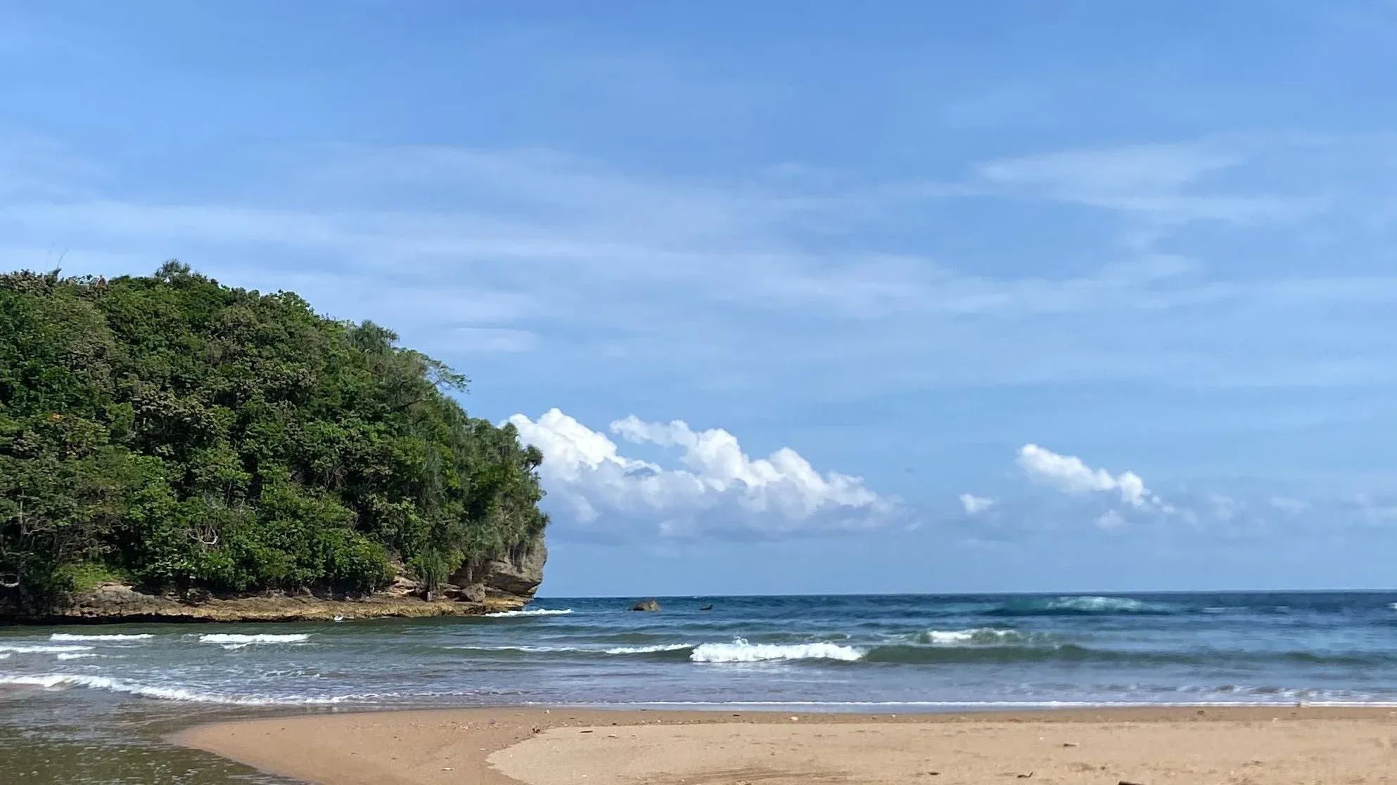Pantai Bantol dengan aliran sungai, pasir, dan tebing hijau