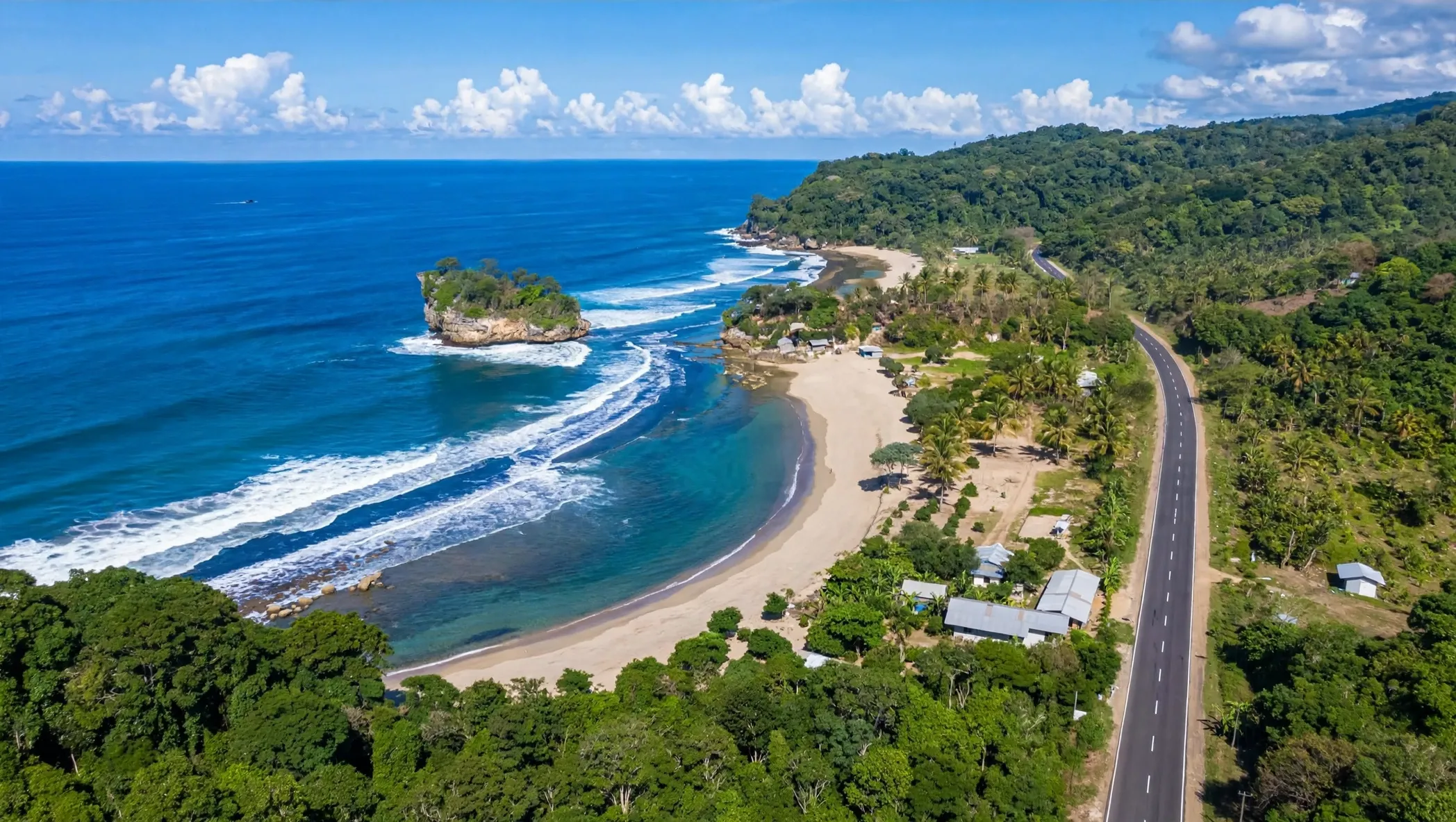Pantai Jelangkung dari udara dengan pulau karang, garis pantai melengkung, dan Jalan Lintas Selatan di sisi pantai