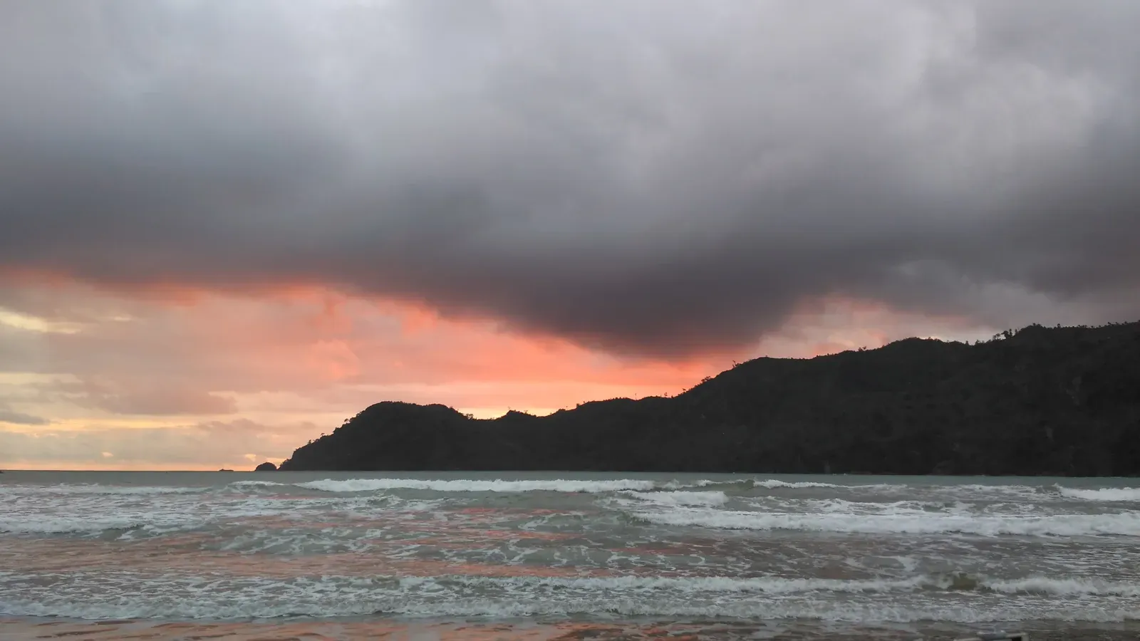 Senja dengan langit jingga di atas ombak Pantai Lenggoksono