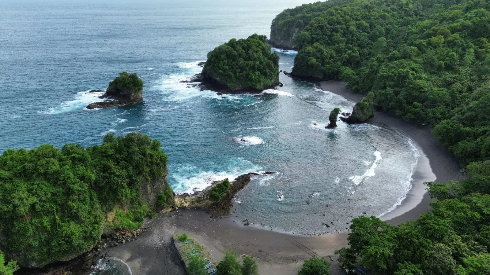 Foto udara Pantai Licin di Ampelgading, Malang, dengan pasir hitam dan tebing hijau